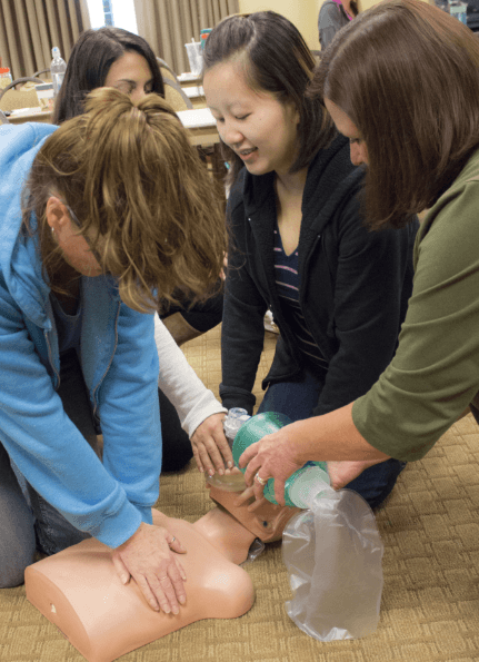 Dental team members practicing CPR on dummy