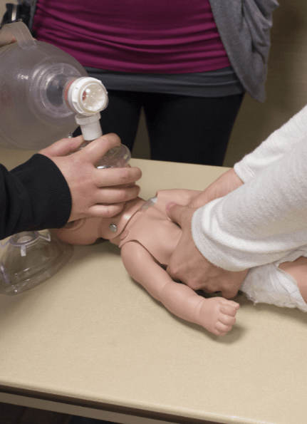 Team practicing infant CPR on dummy