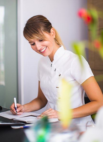 Dental team member at front desk reviewing patient chart