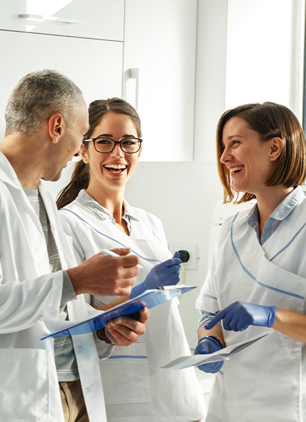 Three dental team members laughing together